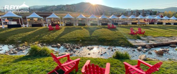 flexx-productions-tent-and-chair-rentals Canopy tents and red chairs set up for a mountainside event along a stream
