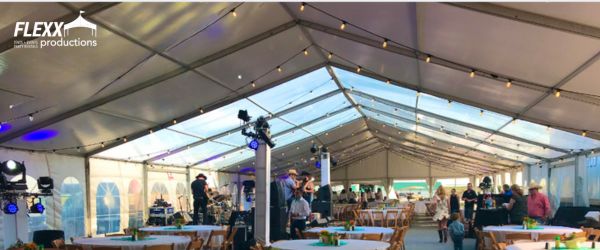 flexx-productions-tent-and-event-rentals A stage, lighting, tables, and chairs set up in a large tent rental for a wedding reception