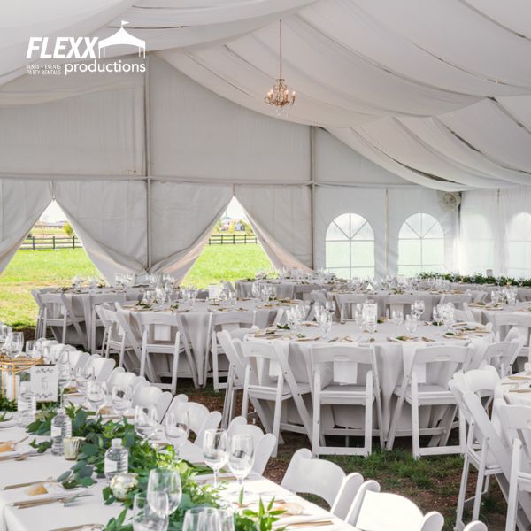 flexx-productions-tent-and-wedding-rentals White tables, chairs, linens, and other event items set up for a wedding reception in a tent rental