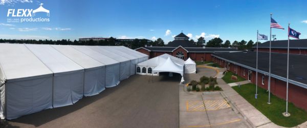 flexx-productions-tent-rentals-cheyenne-frontier-days Multiple tent and canopy rentals set up in a parking lot in front of a brick building for Cheyenne Frontier Days in Wyoming