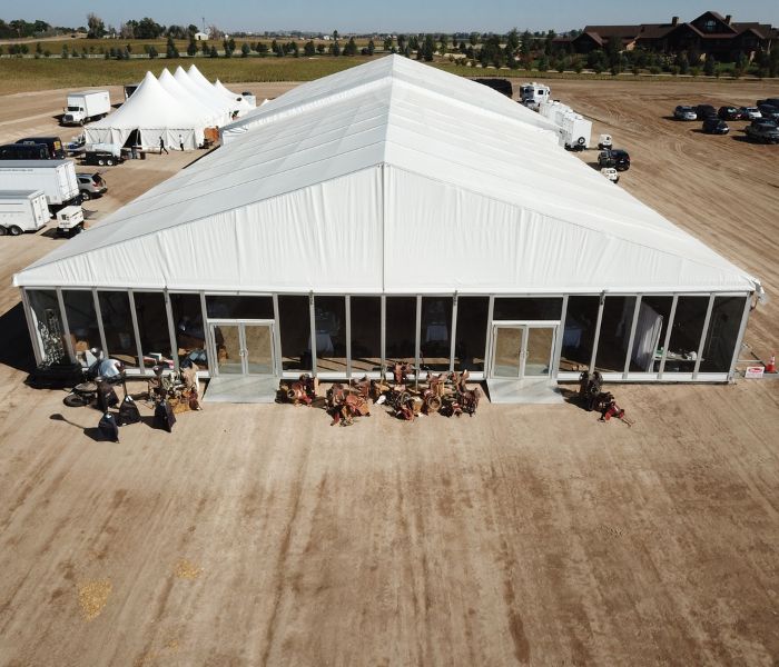 pole-tents-and-structure-tents Large structure tent and smaller pole tent rentals set up outside on a dirt surface