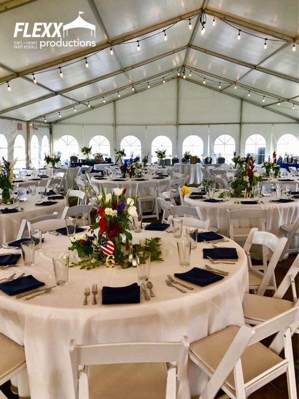 structure-tent-table-and-chair-rentals Large 40x clear span tent rental set up for an event with market string lighting, tables, chairs, and place settings