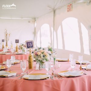 Tables decorated with pink table linens, gold plates, flatware, glassware, and floral centerpieces