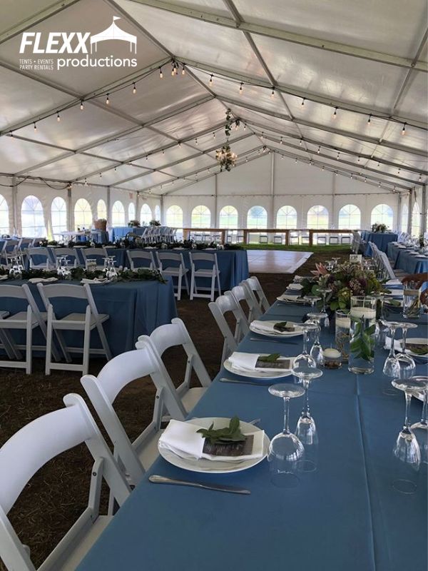 clearspan-structure-tent-wedding-reception Clearspan structure tent set up for a large outdoor wedding reception with tables, chairs, blue linens, and flatware