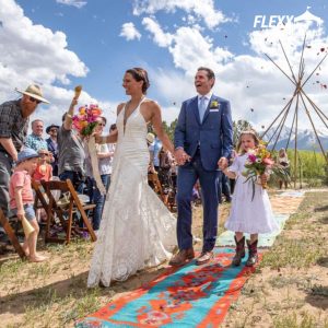 Newlyweds walking down the aisle with their daughter at a mountainside outdoor wedding