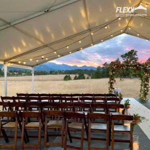 40x30 open-gable structure tent and rustic wood chairs set up for a wedding with mountains and a sunset in the background