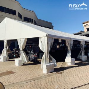 Open-wall clearspan tent with concrete weight covers set up for an outdoor event
