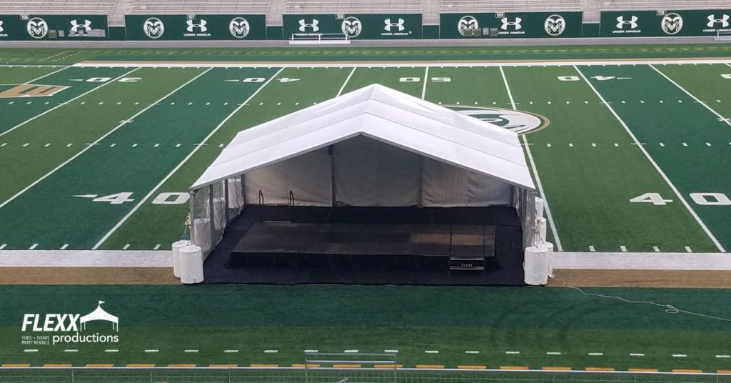 30x clearspan tent with open gables and a stage set up on the CSU Rams football field