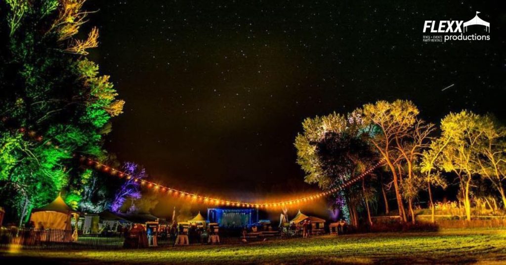 An outdoor event set up with tables, tents, market string lights, ProColor lights, and other party rentals for Halloween