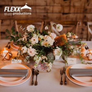 Table set with floral centerpiece, china, chargers, linen napkins, and other party rentals