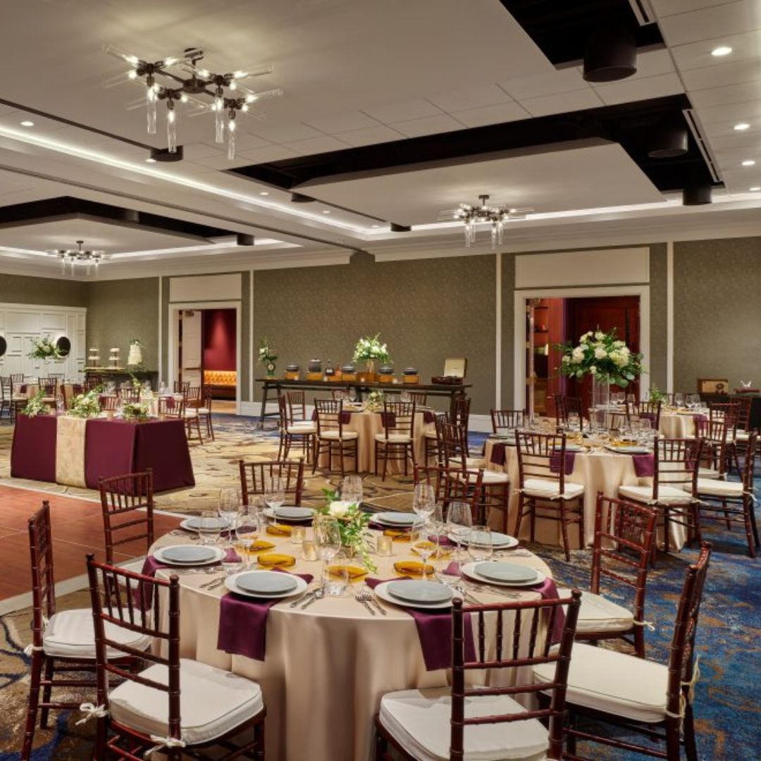 complimentary-linen-samples Several round napa wood tables and chairs decorated in colorful linens, dinnerware, and other decor for an indoor wedding