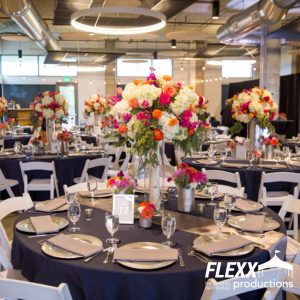 Tables decorated with various colored linens, dinnerware, napkins, china, and large vibrant floral centerpieces 