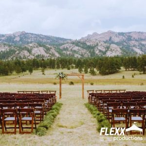 Wedding rentals like chairs and a wedding arch set up outdoors for a mountainside wedding
