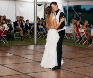 A couple dancing on a dance floor rental under an event tent at their wedding