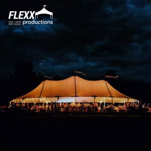 Party tent lit up in the night by lighting rentals for an outdoor event
