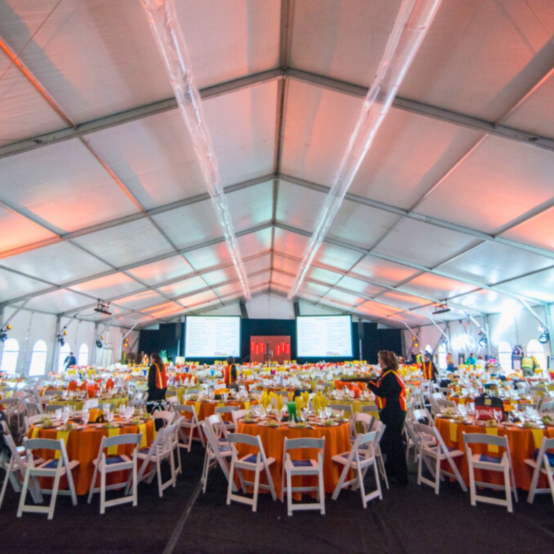 complimentary-services Tables, chairs, and other corporate event rentals set up under a large tent