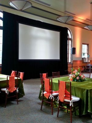 large-screen-and-table-linens Table and chairs draped in green and orange linen rentals for a nonprofit event