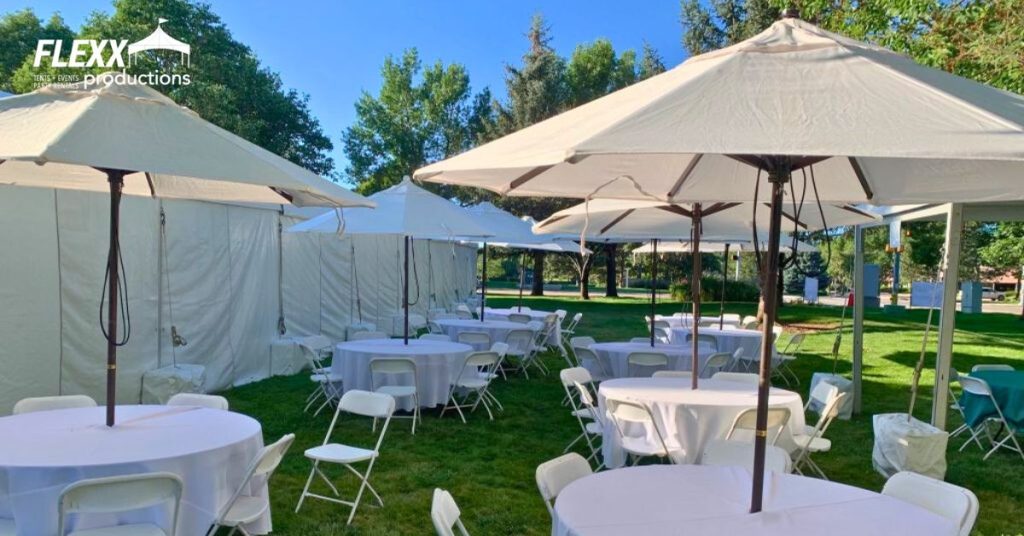 Umbrellas, tables, chairs, a tent, and other party rentals set up for a backyard BBQ