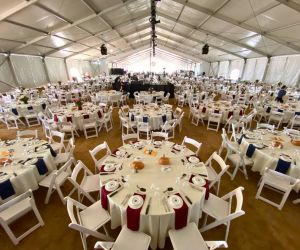 Tables, linens, chairs, and other event rentals for nonprofits set up under a large structure tent