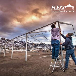 Two FLEXX technicians installing a Clearspan tent in the mountains