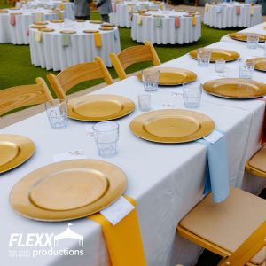 Gold chargers set up on a multiple tables with white linen table cloths
