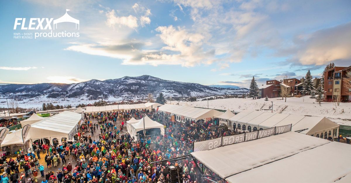 Winter festival in the mountains with multiple tents, stages, and a big crowd