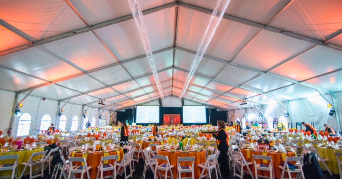 Large Clearspan structure tent rental with event lighting, tables, chairs, and more underneath
